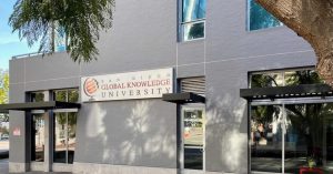 The outside of the San Diego Global Knowledge University offices in a grey building with trees nearby